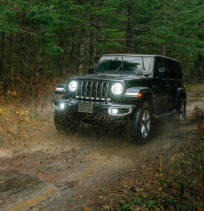 A black Jeep driving on a dirt path